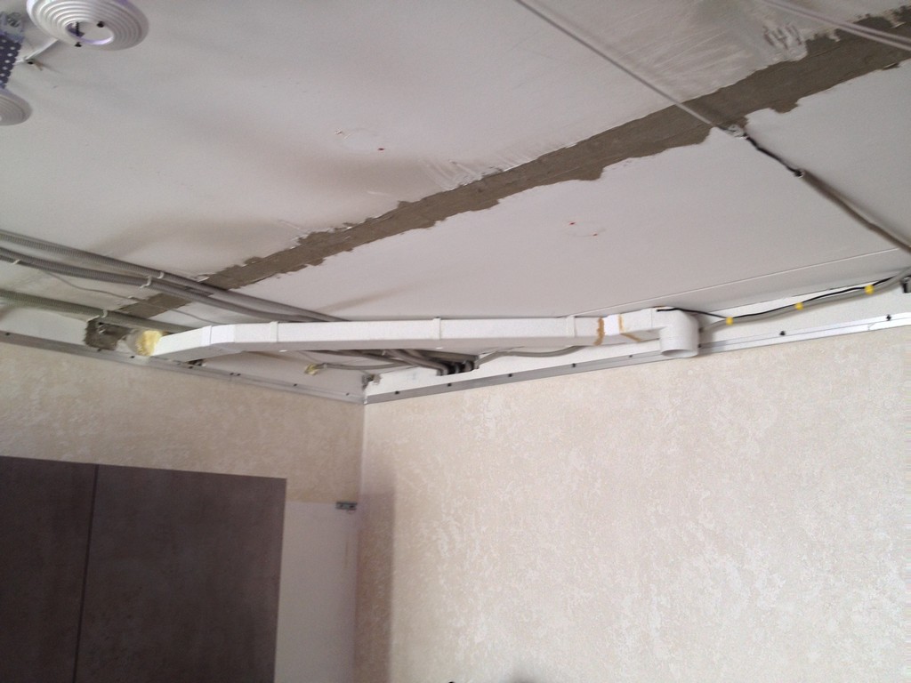Прямоугольный вентканал вытяжки прикреплен к базовому потолку.