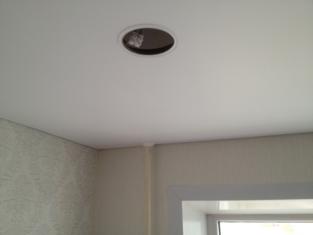 Вырезанное в натяжном потолке отверстие для точечного светильника.