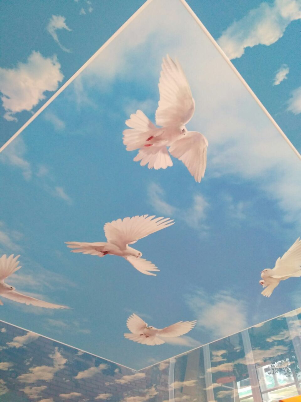 Натяжной потолок с картинкой голубей в небе с облаками.