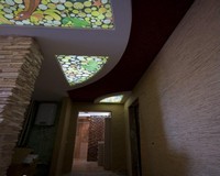 Коридор с мозаикой на натяжном потолке, освещаемом светодиодной лентой за полотном.