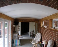 Белый матовый натяжной потолок арочного типа в холле поддерживает свою форму в центре разделительным профилем.