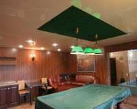 Зелёный замшевый натяжной потолок в цвет сукна бильярдного стола в вырезе бежевого глянца через разделительный профиль.