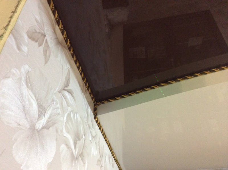 Лаковый натяжной потолок шоколадного цвета с коричнево-золотым декоративным шнуром.