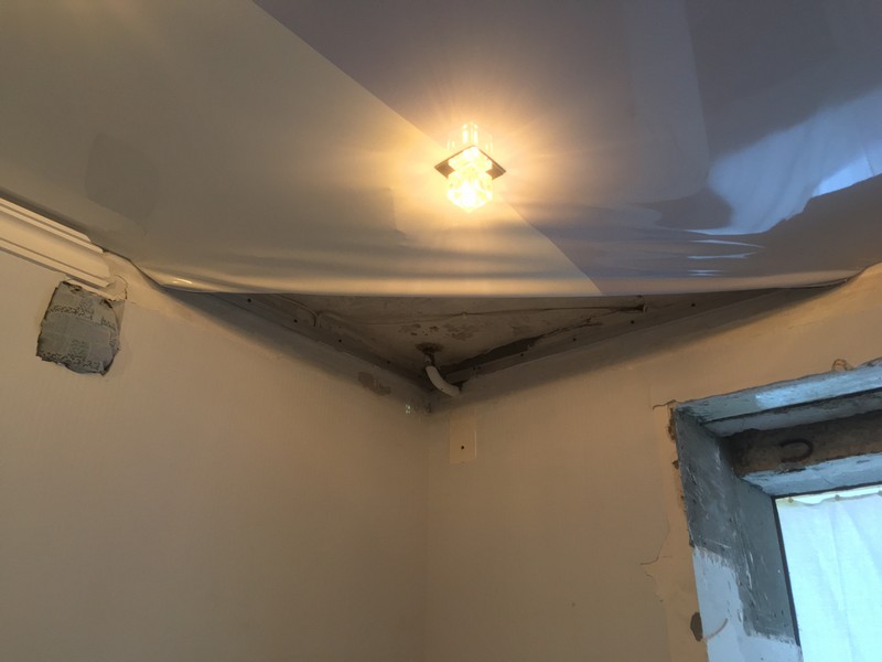 Угол натяжного потолка завернут наверх для замены отопительной трубы.
