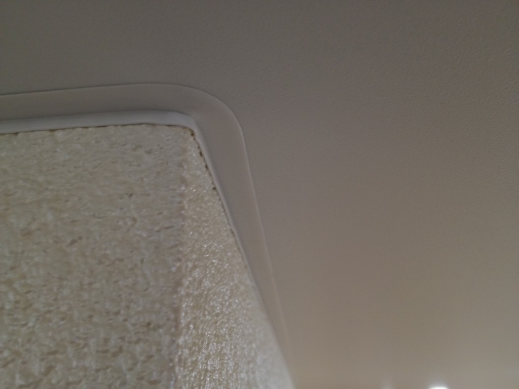 Внешний угол натяжного потолка с декоративной лентой.