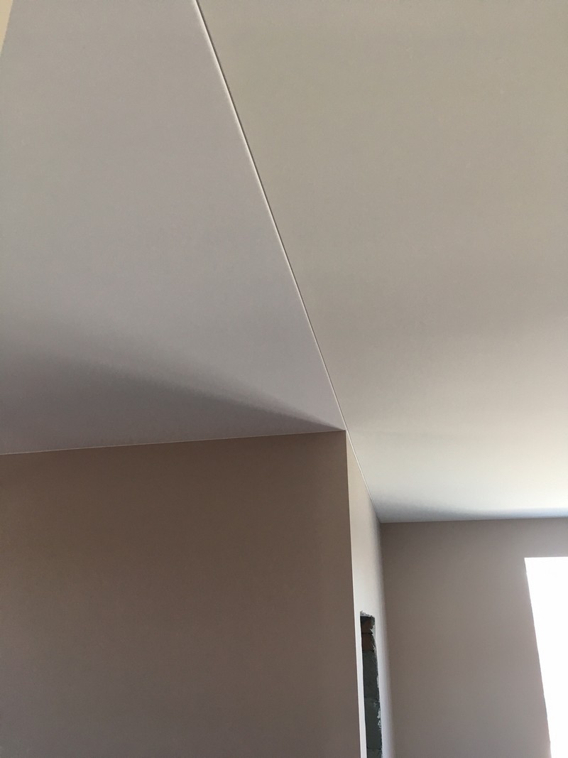 Бежевый и белый тканевый потолок заправлены в один профиль.