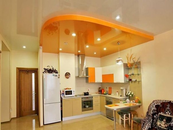 Морковного цвета 2-уровневый натяжной потолок над кухонной зоной.